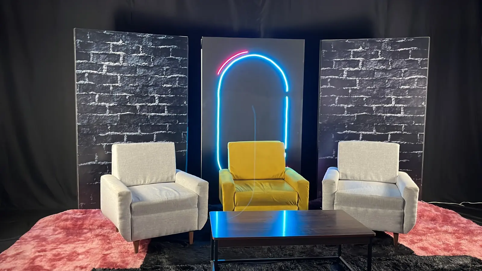 Set de podcast con muro de ladrillo, neón y tres sillones, listo para un podcast para boda